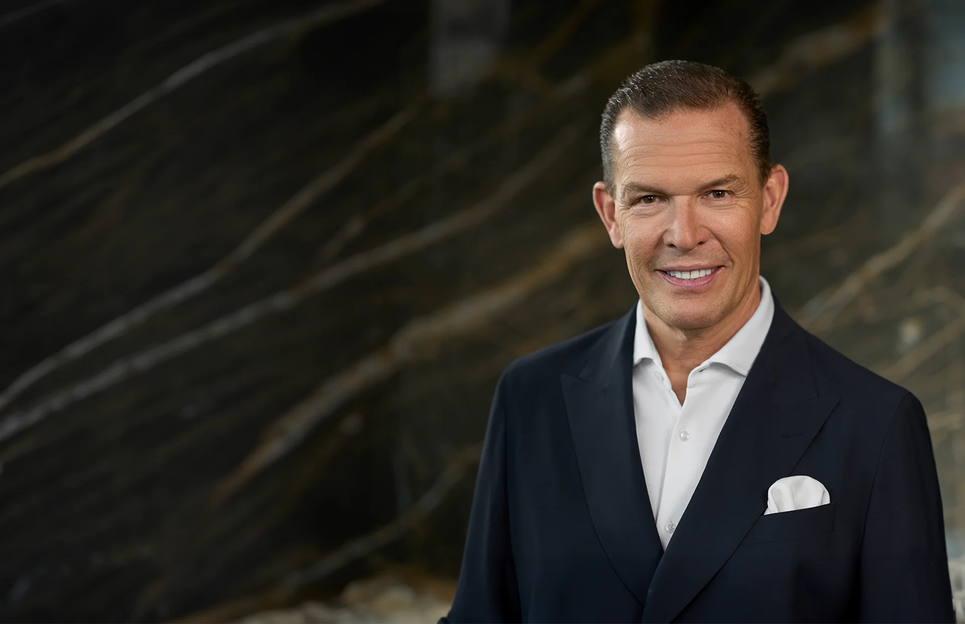 Daniel Grieder in camel-farbigen Anzug vor dunklem Hintergrund (Foto)